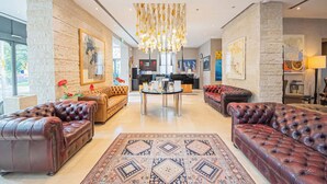 A spacious lobby with leather sofas, a central coffee table, and a chandelier. - Century Hotel (Parma)