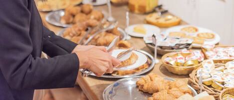 A buffet setup with various food items and a person serving food.