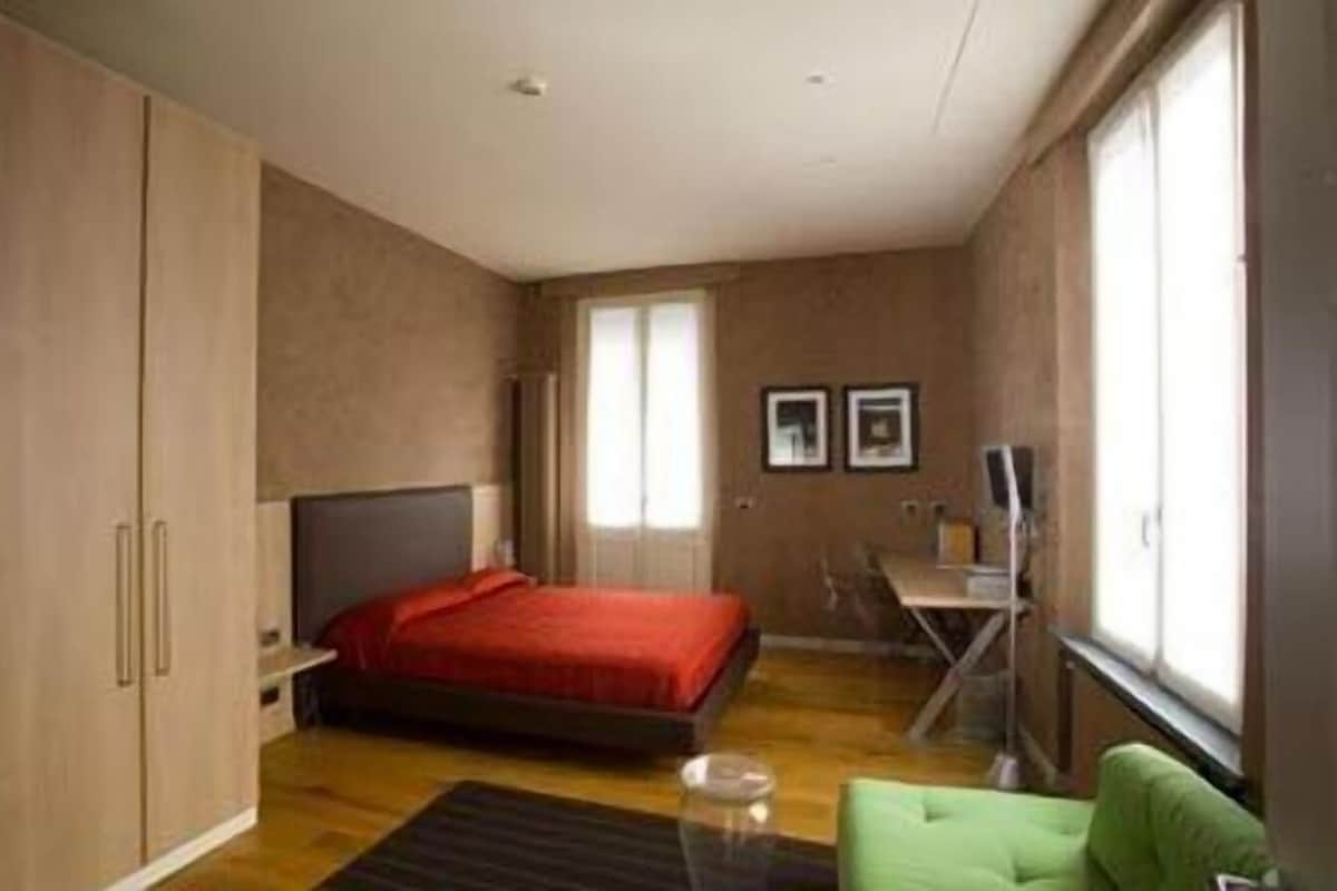 A bedroom with a bed, a desk, a chair, and a wardrobe.