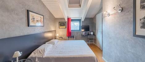 Une chambre à coucher avec un lit, une table de chevet, une lampe et une fenêtre avec un rideau rouge.