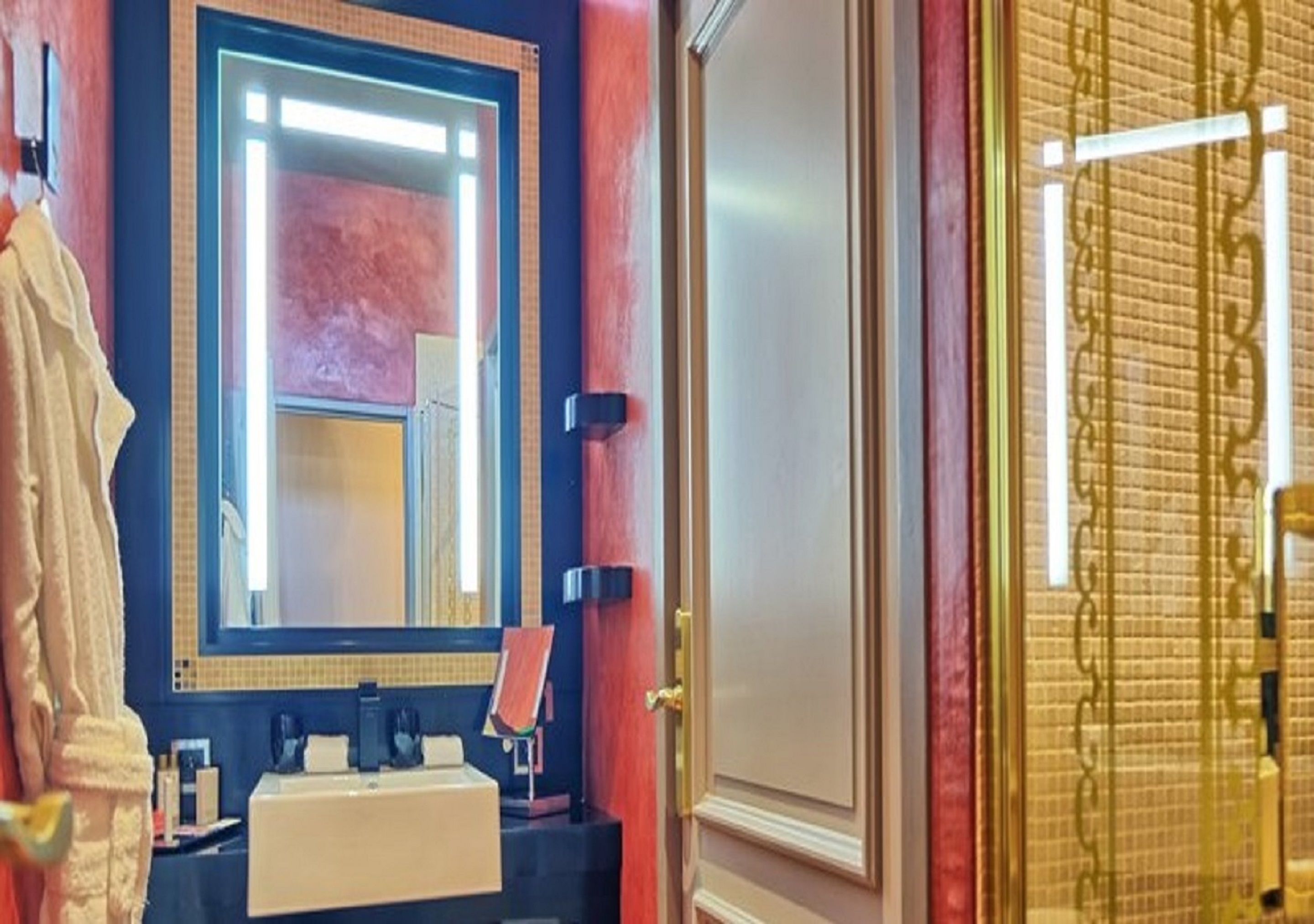 A bathroom with a large mirror, a sink, and a towel rack.
