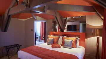 A bedroom with a bed, pillows, a nightstand, a TV, and a lamp.