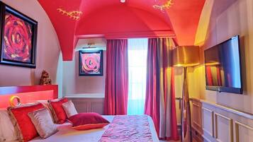 A bedroom with a large bed, red and white bedding, a ceiling with a red arch, and a flat-screen TV mounted on the wall.