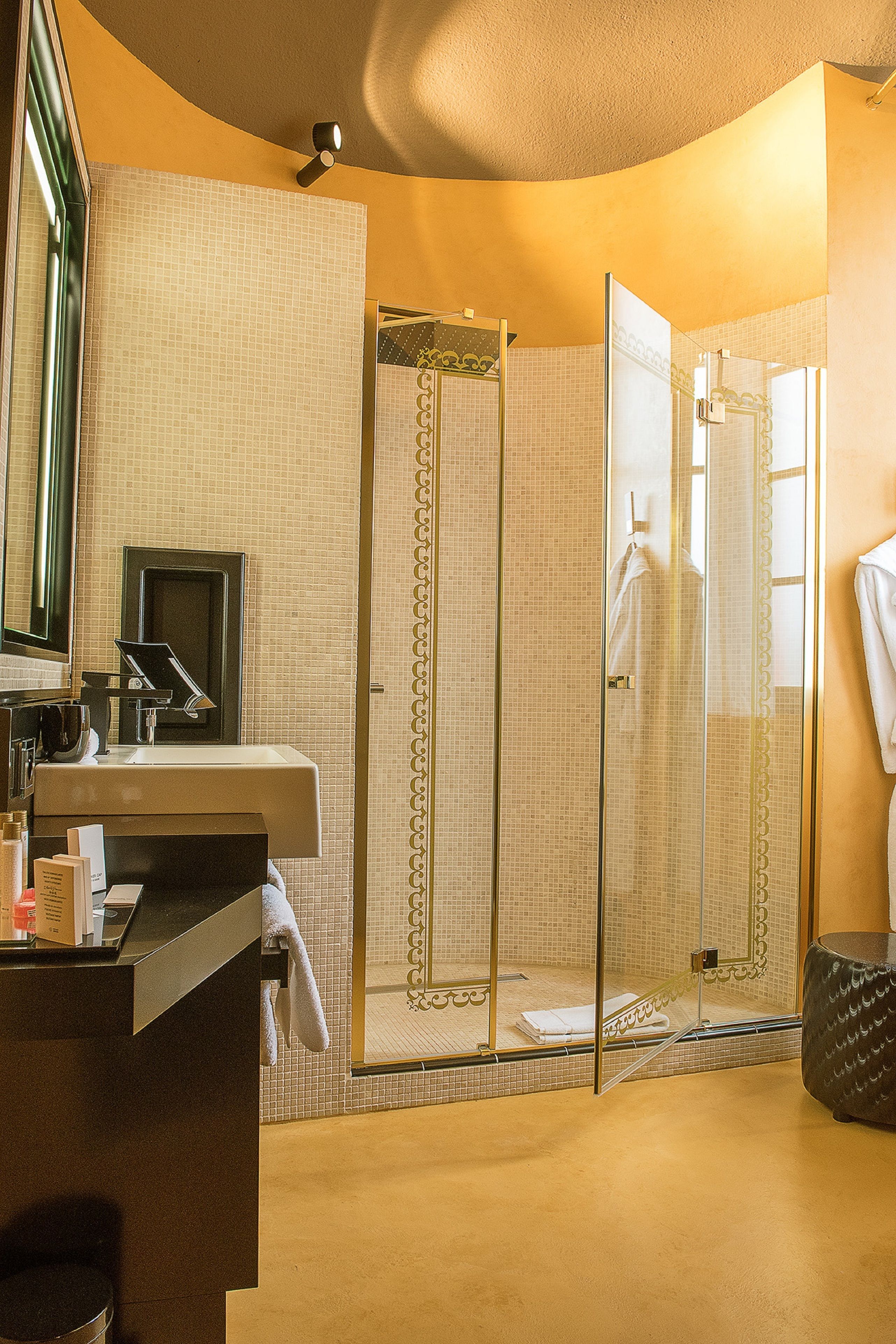 A bathroom with a glass-enclosed shower, a sink, and a mirror.