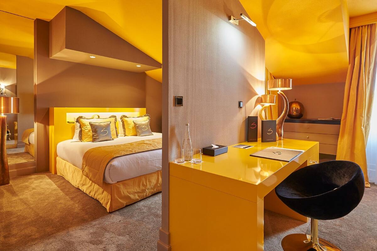 A modern hotel room with a large bed, a desk, and a chair.
