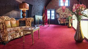 Een knus zithoekje met een comfortabele bank, een bijzettafeltje en een grote vaas vol bloemen.