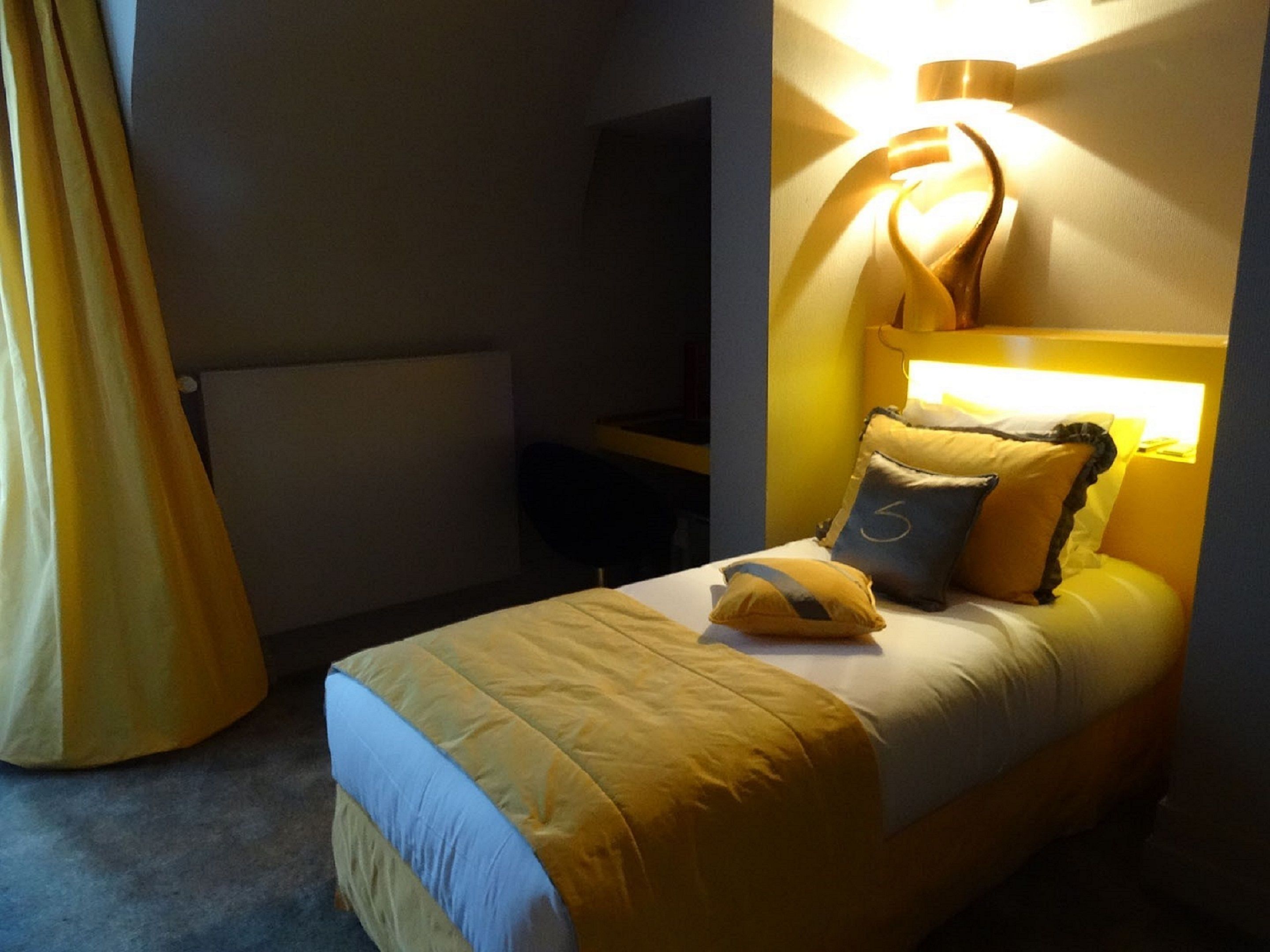 Une chambre à coucher avec un lit, des oreillers et un luminaire fixé au mur.