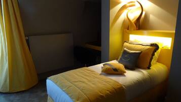 Une chambre à coucher avec un lit, des oreillers et un luminaire fixé au mur.