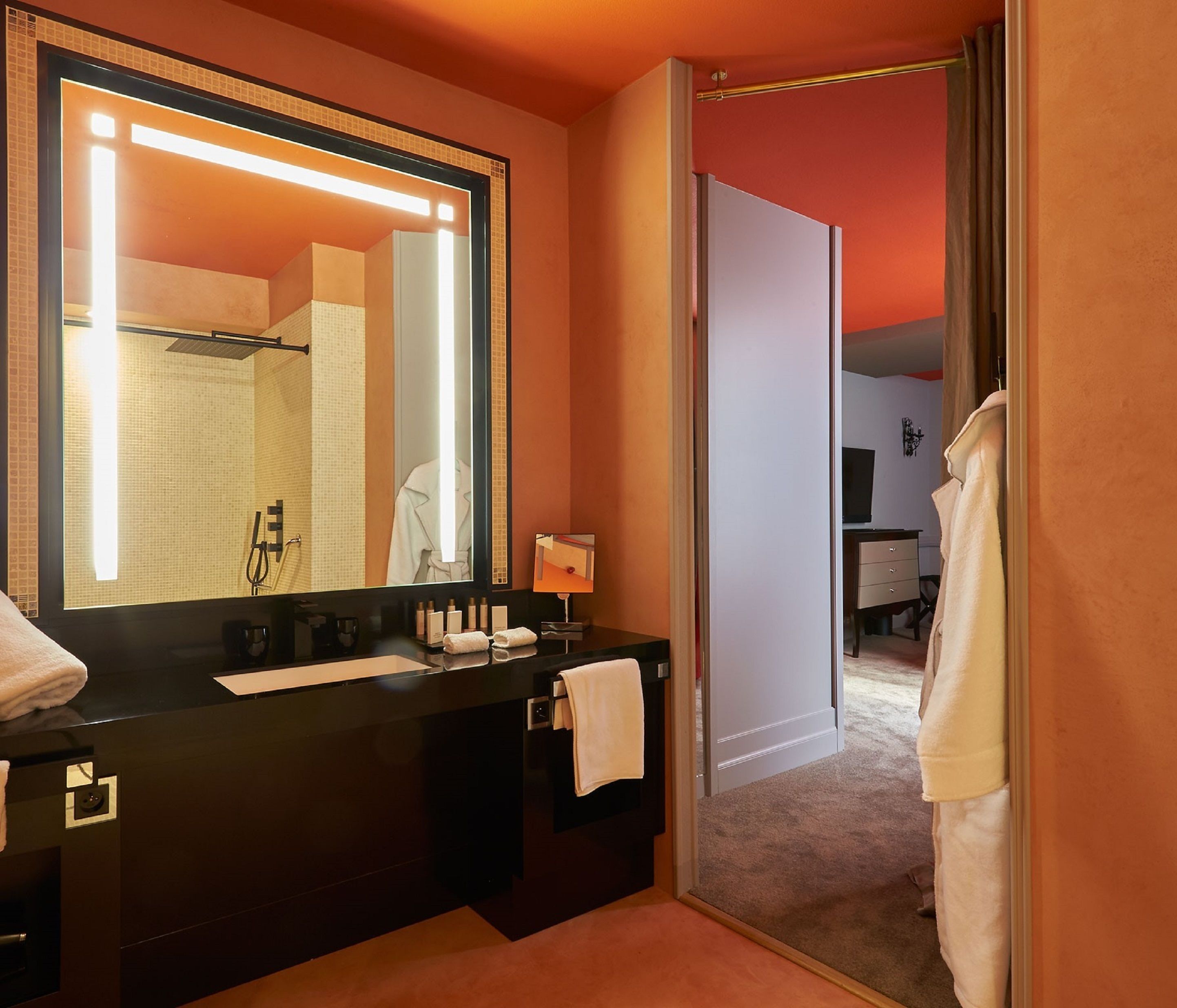 Un bagno moderno con uno specchio grande, un piano di lavoro nero e un porta asciugamani.