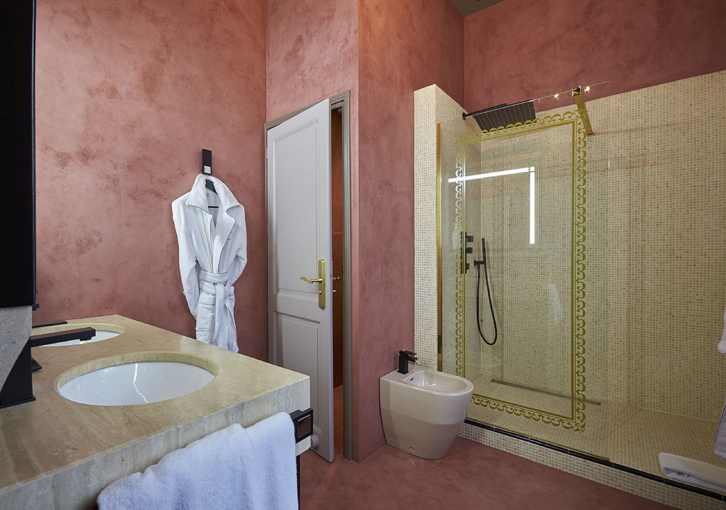 A bathroom with a large mirror, two sinks, a bidet, and a shower enclosure.