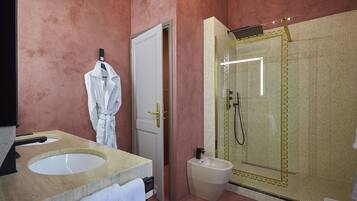 A bathroom with a large mirror, two sinks, a bidet, and a shower enclosure.