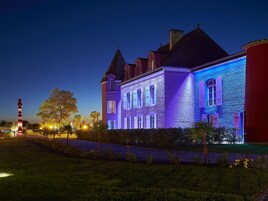 Um edifício histórico com janelas iluminadas e uma torre imponente.
