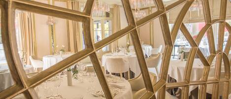 A dining area with round tables set for a meal, featuring white tablecloths and elegant table settings.