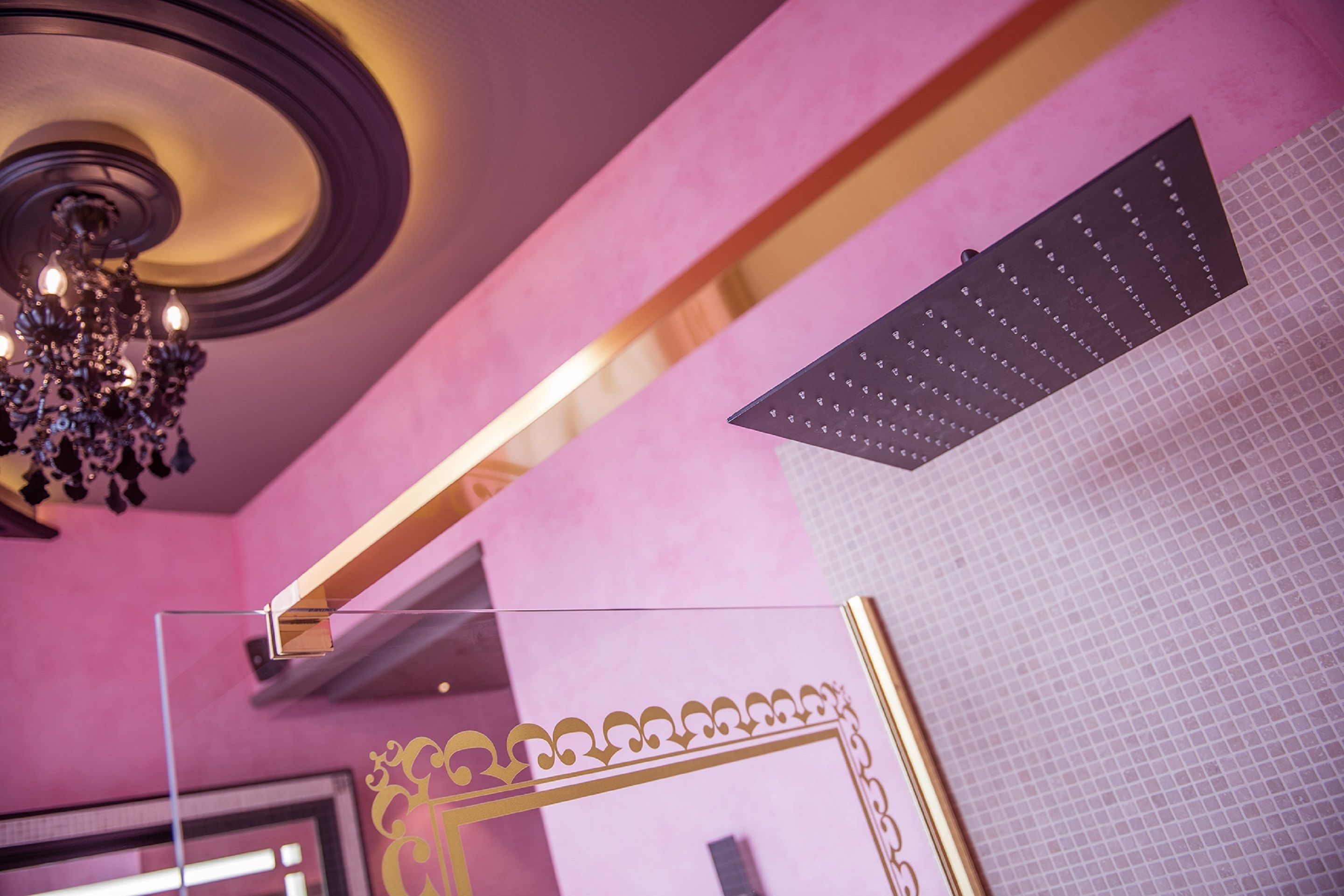 A room with a chandelier, a mirror with a gold frame, and a ceiling with a circular light fixture.