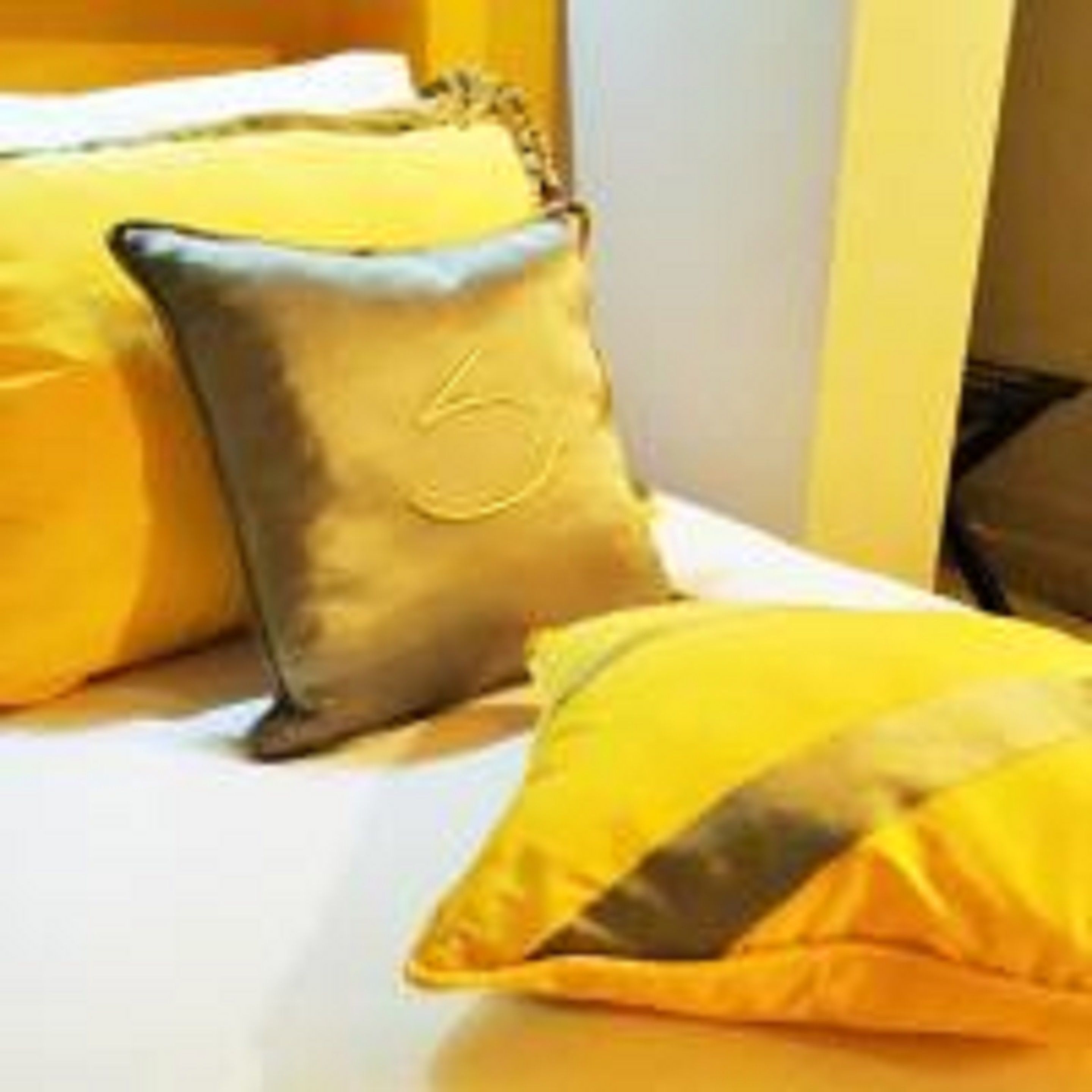 A bed with yellow and grey pillows.