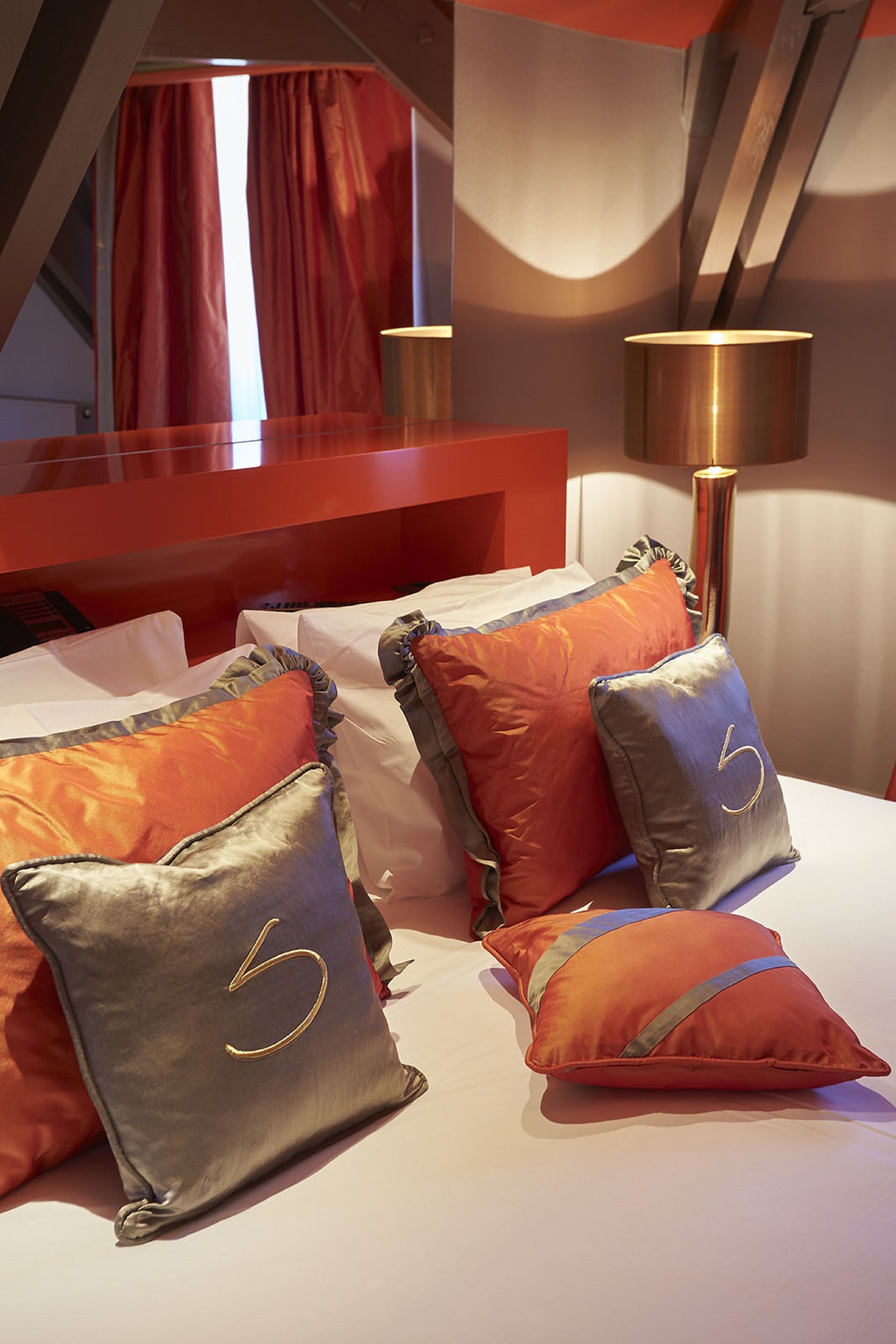 Une chambre d’hôtel avec un lit, des rideaux rouges et une lampe.