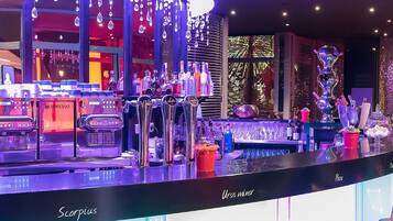 A bar area with espresso machines, a counter, and various bottles and glasses.