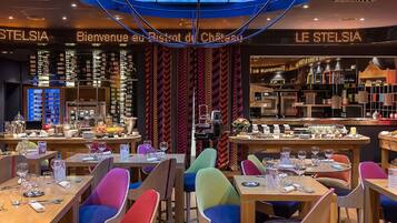 Un restaurant avec des chaises aux couleurs vives, une variété de plats exposés et une enseigne sur laquelle on peut lire « LE STELSI ».