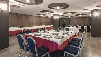 Un salón de banquetes con mesas redondas dispuestas para comer, equipado con sillas y vajilla.