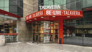 The exterior of a restaurant named 'TALAVERA' with a glass entrance and a red awning.