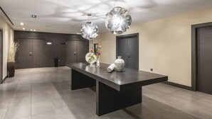 A modern reception area with a long reception desk, two large decorative pendant lights, and a vase with flowers.