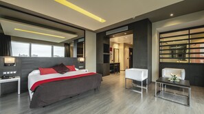 A modern hotel room with a large bed, bedside tables, a desk, and a seating area. - Be Live City Center Talavera (Talavera de la Reina)