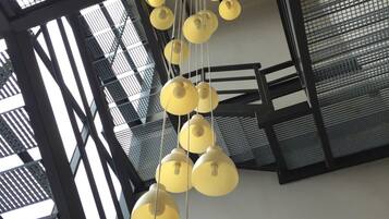 Un interior moderno con varios candelabros colgantes amarillos y una estructura de escaleras metálica.