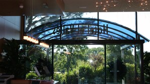 A reception area with a glass entrance, a reception desk, and a view of greenery outside. - Hotel El Vallés (Briviesca)