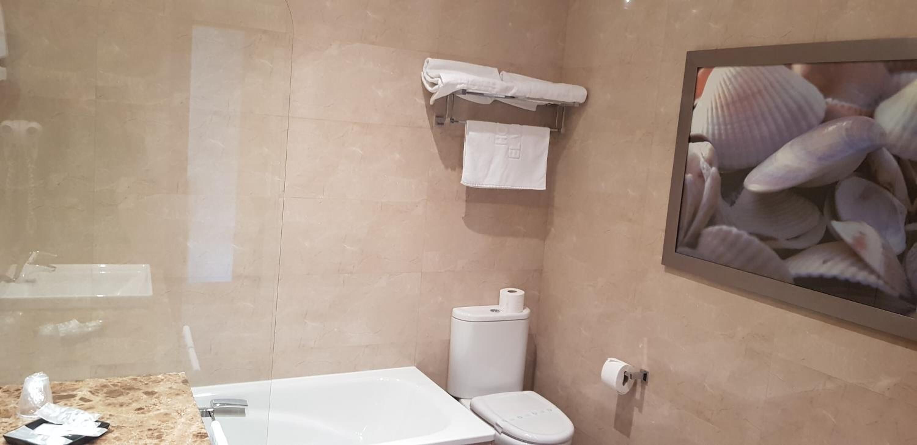 A bathroom with a marble sink, a toilet, and a towel rack with a towel.