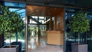 A hotel entrance with a reception desk, glass doors, and potted plants. - Hotel El Vallés (Briviesca)