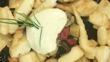 Un plato con patatas fritas, una cucharada de crema agria y una ramita de cebollino.