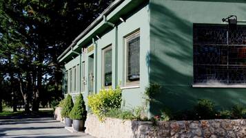 Un edificio con base de piedra y paredes exteriores verdes, con una hilera de ventanas y una puerta.