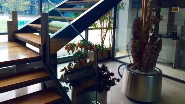 A modern staircase with glass railings and wooden steps, leading to a second-floor area with a view of greenery outside. - Hotel El Vallés (Briviesca)