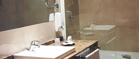 A modern bathroom with a large mirror, a sink, a shower, and a bathtub.