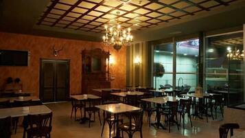 Un restaurante con techo de diseño enrejado, candelabros y una combinación de muebles de madera y metal.