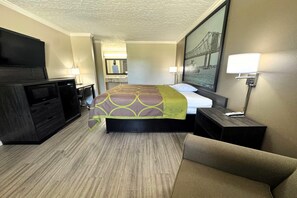 Ein Hotelzimmer mit Bett, Fernseher, Schreibtisch und Stuhl.