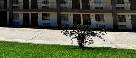 A multi-story motel with a flat roof, multiple balconies, and a parking lot in front.