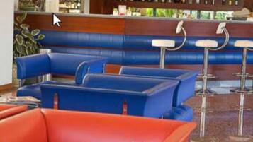 Un'area bar con sedute blu e rosse, tra cui cabine e sgabelli da bar.