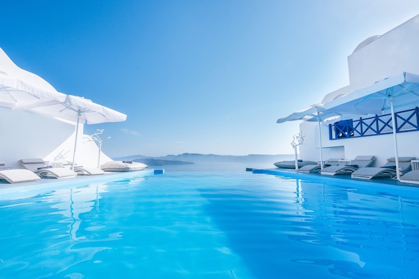 Una piscina al aire libre, sombrillas, sillones reclinables de piscina