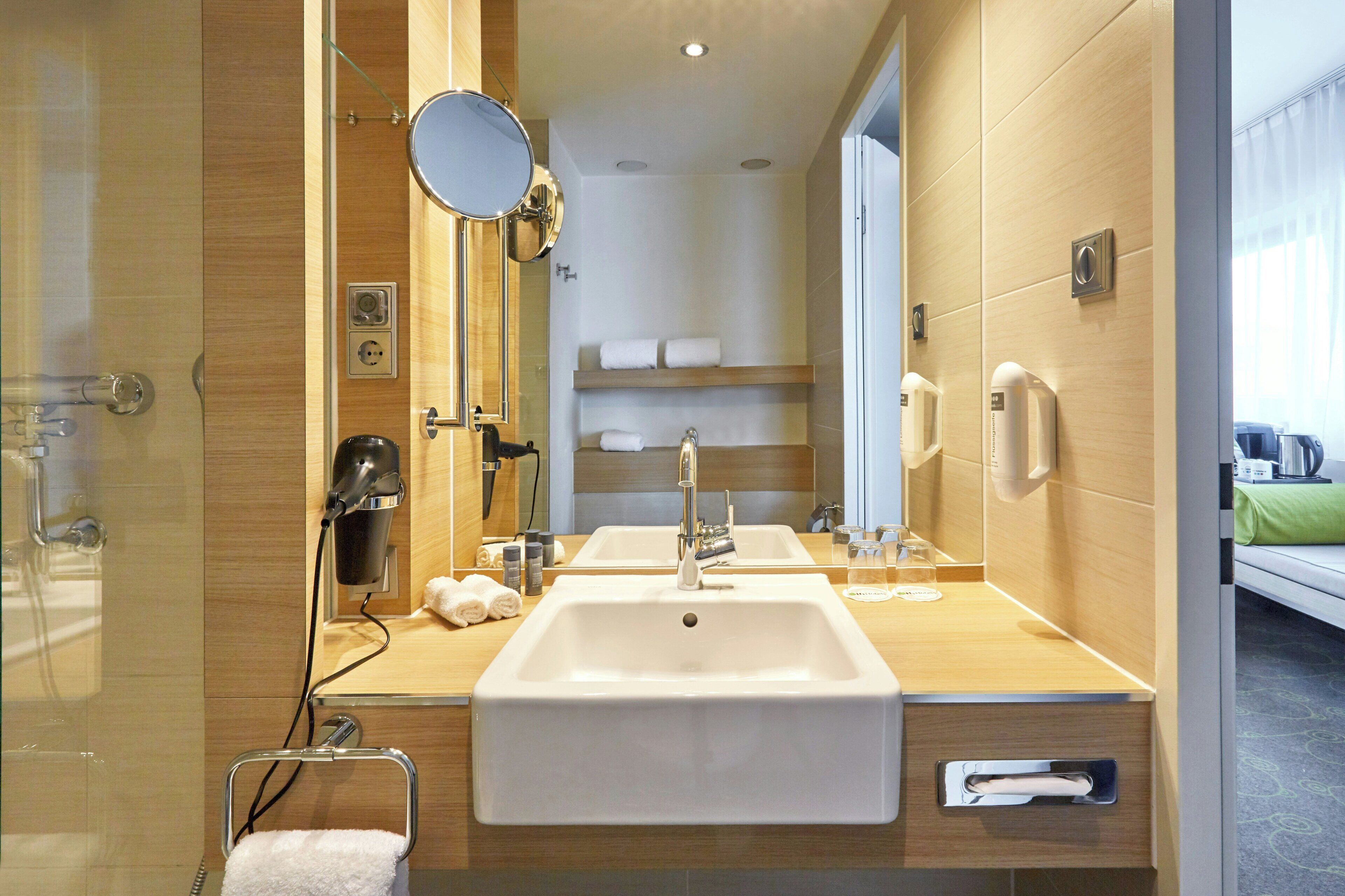 Un bagno moderno con un doppio lavandino, un asciugacapelli, uno specchio e un portasciugamani.