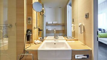 A modern bathroom with a double sink, a hairdryer, a mirror, and a towel rack.