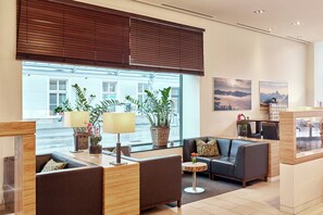 A modern hotel lobby with a seating area, large windows, and decorative plants. - Hotel Salzburg-Hauptbahnhof (Salzburg)