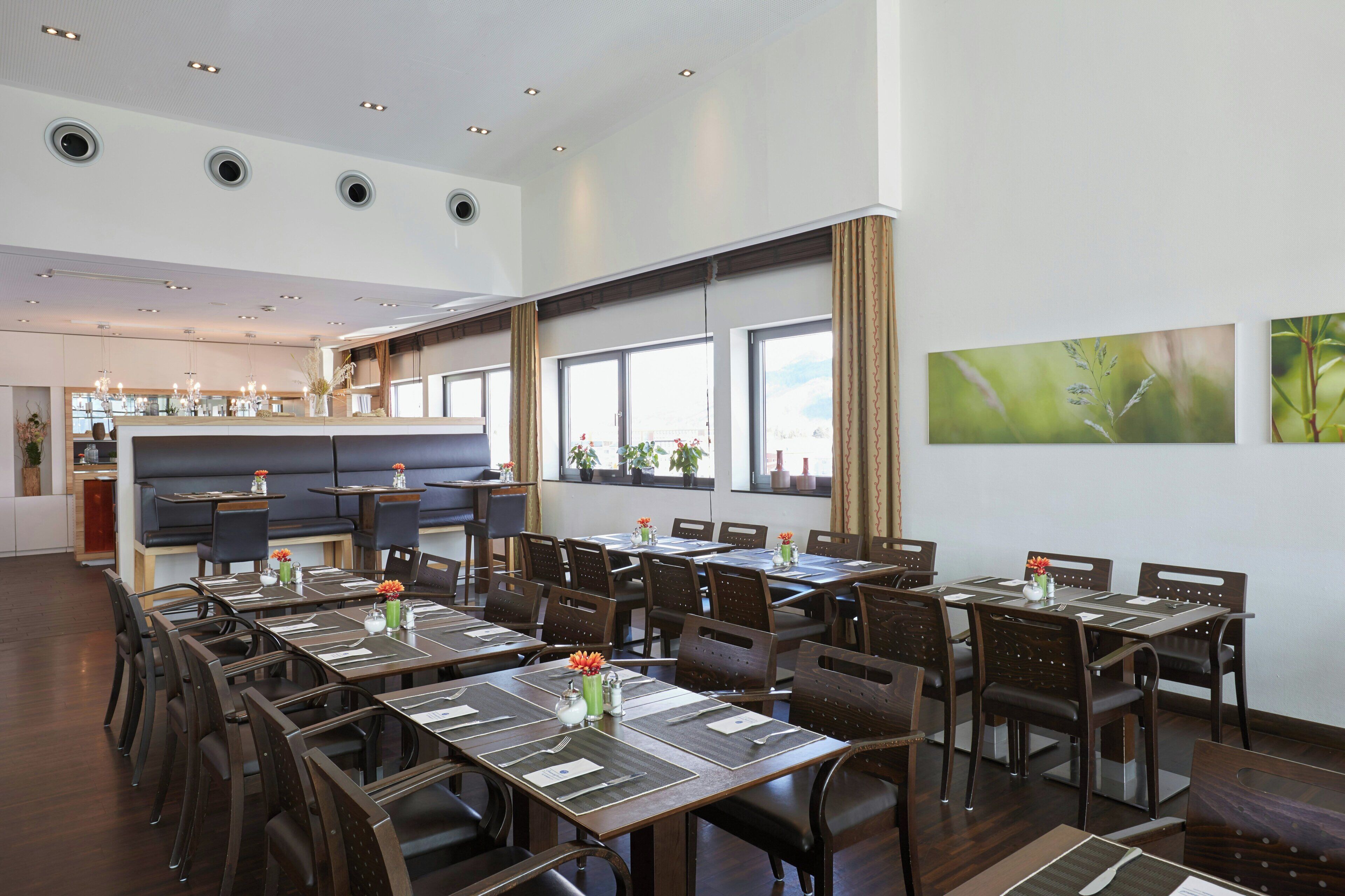 Un restaurante con varias mesas, sillas y una zona de bar.