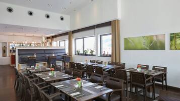 Un restaurante con varias mesas, sillas y una zona de bar.