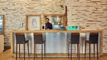 A bar area with a stone wall backdrop, a bar counter, and three bar stools.