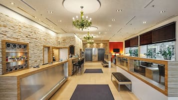 A modern hotel lobby with a stone wall, a reception desk, seating area, and a chandelier.