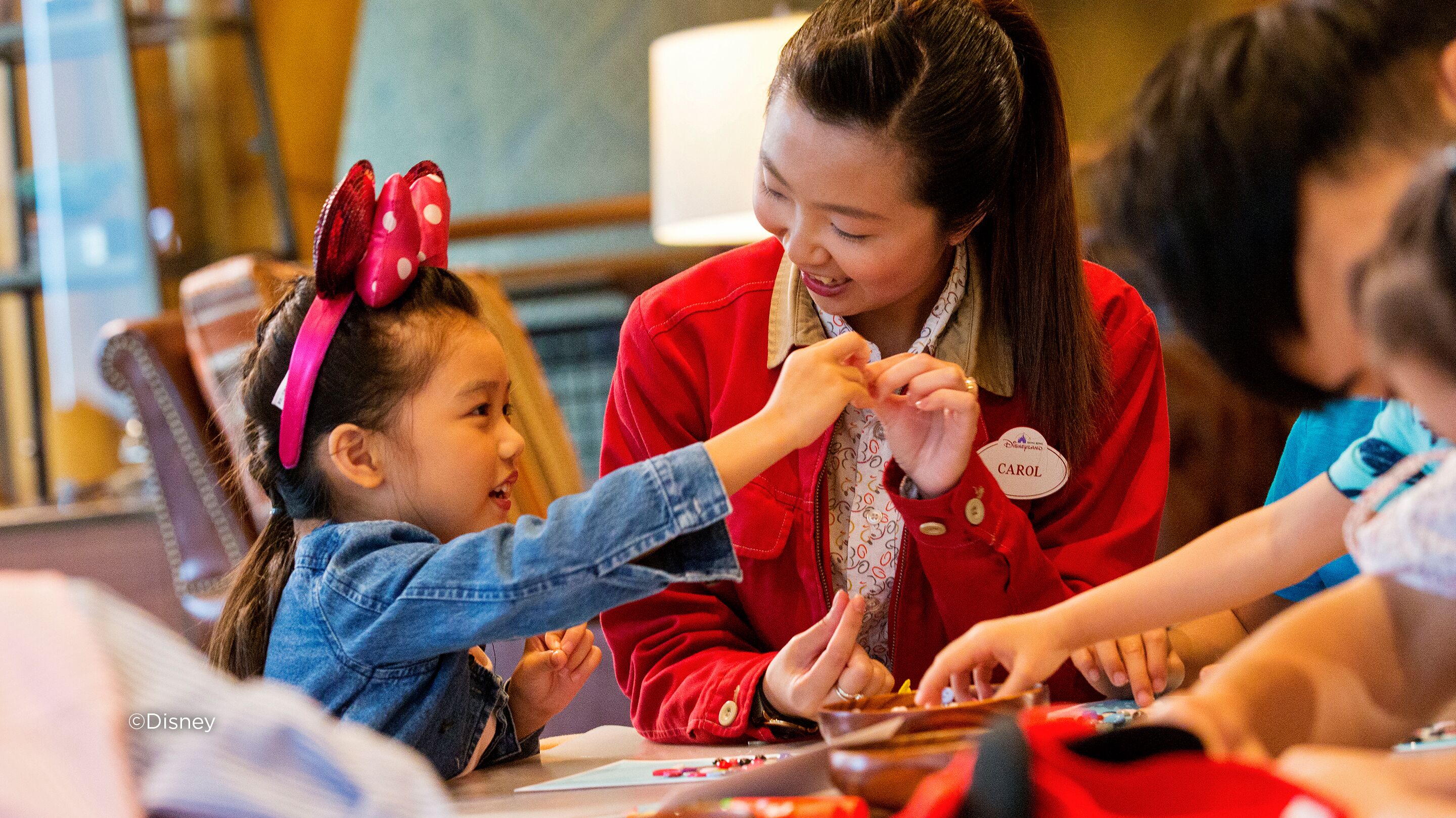 A group of people engaged in an activity at a table, with a Disney logo visible.