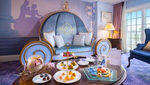 Une chambre luxueuse avec un canapé bleu, une table à manger agrémentée d’un service à thé et une lampe décorative.