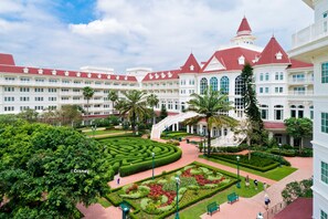 A large hotel with a central courtyard featuring a maze, palm trees, and a red-roofed building.