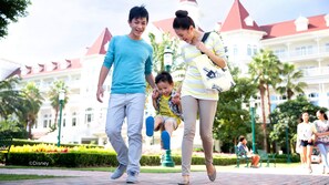 Una familia caminando por un sendero pavimentado, con un edificio grande al fondo.